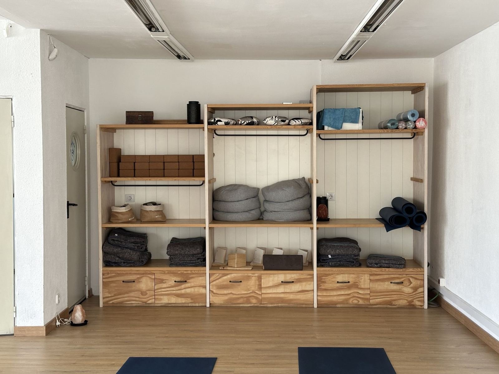 Estantería de madera con bloques de corcho, cojines, mantas y esterillas